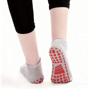Low cut kids gripper socks in grey with red non-slip grips on the soles, displayed from behind.