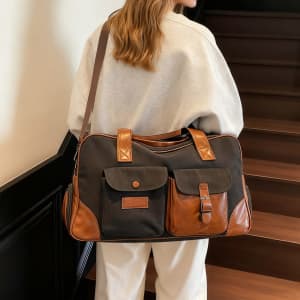 A vintage canvas duffle bag in navy and brown, featuring multiple pockets and a shoulder strap.