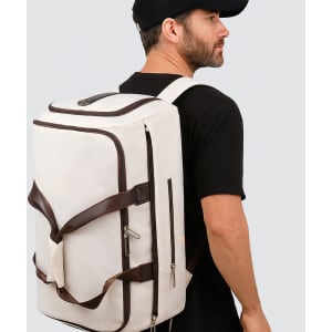 A white convertible backpack duffel garment bag with brown straps, displayed on a person wearing a black cap and shirt.