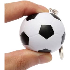 A hand holds a small black and white football-shaped stress reliever attached to a keyring.
