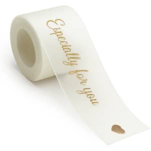 A roll of ivory organza ribbon with gold text and a small heart design. The product has a logo on the packaging.