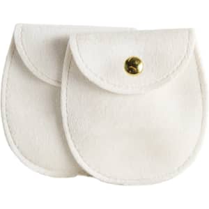 A pair of oval white velvet jewelry pouches with gold snap closures and a logo on one.