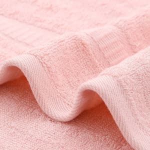 A bamboo fibre towel in a soft pink hue, featuring a textured surface and edges. The towel is presented with subtle folds.
