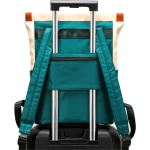 A teal convertible nylon backpack with adjustable straps, resting on a black suitcase. Features include a zippered pocket and a logo.