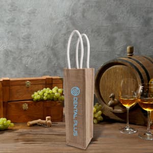 A jute wine carrier in natural brown with white handles, surrounded by grapes and wine glasses.