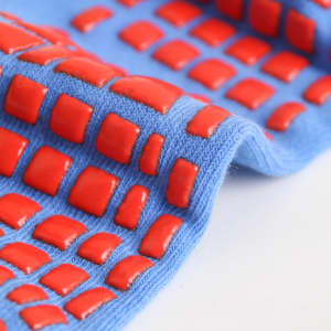 Blue socks featuring red textured grips, designed for added traction. The product has a logo on the fabric.