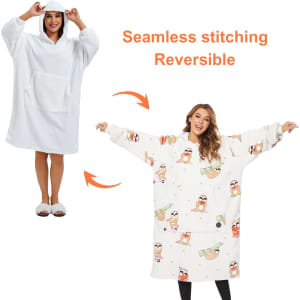 A reversible, wearable blanket in white and patterned designs, featuring a hood and pocket.