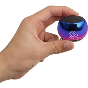 A hand holding a small, round, iridescent blue and purple Mini Bass Wireless Speaker with a logo.