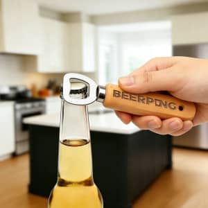 A drink bottle opener with a wooden handle and metal top, held above a bottle in a kitchen setting.