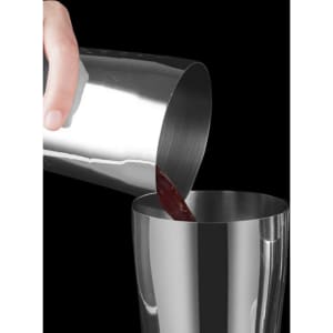 A stainless steel cocktail shaker with a sleek silver finish, pouring liquid into a glass.
