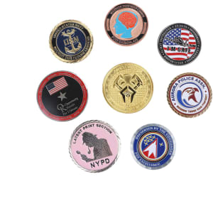 A collection of commemorative gold coin pins in various colours and designs, featuring different logos and emblems.