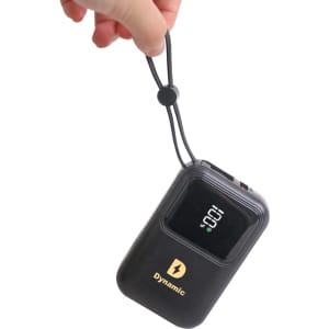 A hand holds a black portable power bank with a digital display and a logo, featuring a convenient strap.