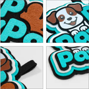A custom felt hanging tag featuring a black, turquoise, and brown dog design on a soft felt background.