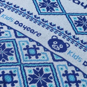 A close-up of a patterned fabric in shades of blue featuring geometric designs and a bear logo.