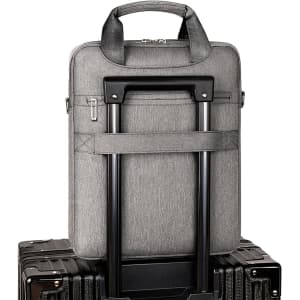 A grey business sling laptop bag with a handle and trolley strap, resting on top of two dark suitcases.