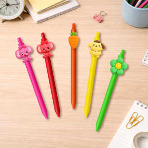 A set of five custom PVC pens in pink, red, orange, yellow, and green, each with unique character tops, on a wooden table.
