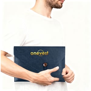 A navy PU leather folder with a button closure, featuring a logo on the front, held by a person.