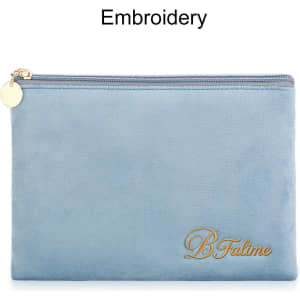 A durable flat makeup bag in soft blue with a gold embroidered logo and a zip closure.