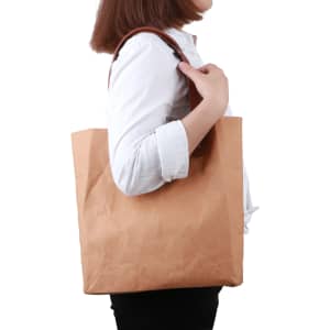 A brown washable kraft paper bag with a PU handle, featuring a simple design and a side view of a person holding it.