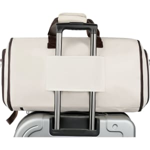 A convertible backpack duffel garment bag in cream and brown, attached to a silver suitcases' handle.