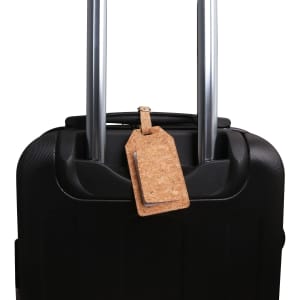 A cork luggage tag in a natural tan colour attached to black suitcase handles. The tag features a logo.