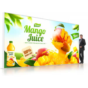 A backlit LED light box display features vibrant mango juice graphics and a drink bottle, with a person beside it for scale.