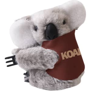 A grey koala plush toy with large ears, holding a brown pouch, featuring a logo on it.