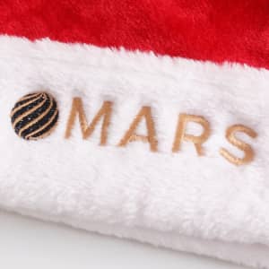 A plush Santa hat featuring a bright red exterior and white trim, with a logo embroidered on it.
