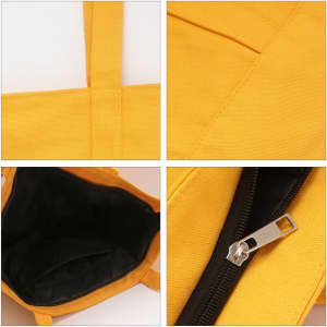 A yellow canvas zippered tote shoulder bag with black interior and a silver zipper. It has sturdy handles and features a logo.