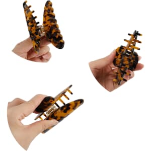 A set of tortoiseshell acetate hair clips being held in hand, showcasing their design and structure.