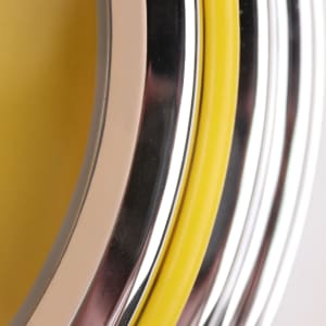 A close-up of a double ring wall clock with yellow, silver, and chrome accents. The design features a glossy finish.