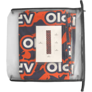 A small table runner in vibrant red and blue patterns, packaged in a clear zippered pouch, with a logo visible.