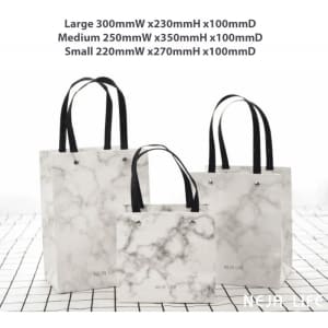 A set of three marble-patterned bags with black handles, in large, medium, and small sizes, featuring one logo.