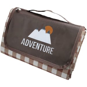A medium picnic blanket in brown with a digital print featuring mountains and checkered edges. Includes a carry handle and logo.