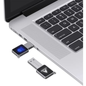 A square grey flash drive plugged into a laptop, featuring a logo and a blue light indicator.