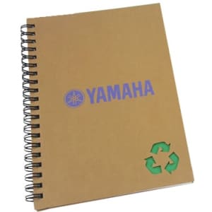 A brown spiral-bound notebook featuring a logo and a recycling symbol. The cover has a textured finish.
