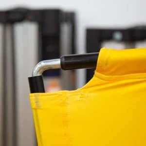 A close-up of a corner of a yellow tent billboard banner, displaying a metal frame connection.