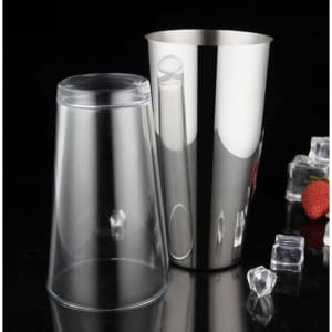 A cocktail shaker set featuring a transparent plastic cup and a shiny stainless steel shaker, placed on a dark surface with ice and fruit.