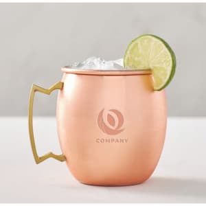 A copper mug featuring a gold handle, filled with ice and garnished with a slice of lime. It has a logo on the front.