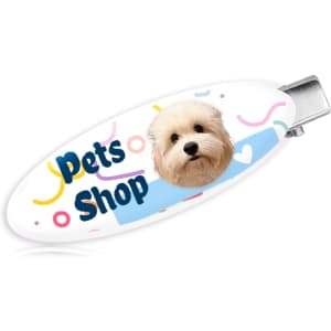 An oval acrylic hair clip featuring a dog's face and colourful abstract patterns, with a logo.