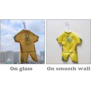A mini jersey in yellow displayed on glass and a smooth wall, featuring a logo and detailed design.
