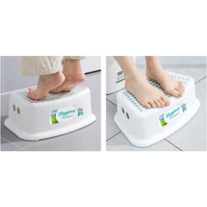 A white step stool with textured surface and a logo, being used with bare feet on a tiled floor.