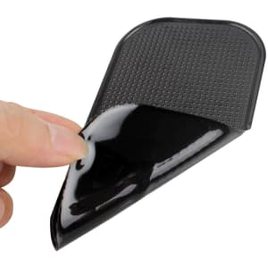A black dashboard mat being lifted, showcasing its textured surface and flexible design.