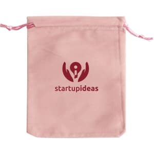 A pink velvet drawstring bag with a logo printed on the front. The bag has matching pink drawstrings.