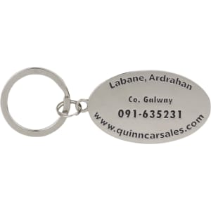 A silver oval keyring with an attached ring, featuring engraved details and a logo.