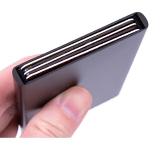 A hand holding a sleek black metal RFID card holder with several cards visible inside.