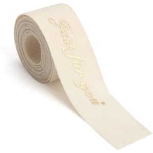 A roll of cream-coloured cotton ribbon featuring a gold hot-stamped message. It has a branding logo.