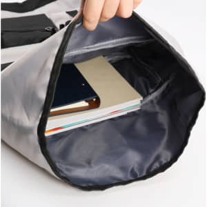 A roll top backpack in grey with a spacious interior, holding notebooks and a folder. Features a brand logo.