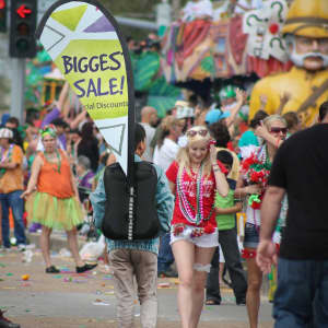 A Teardrop Backpack Flag features a vibrant design, prominently displaying a logo, in a bustling festive environment.