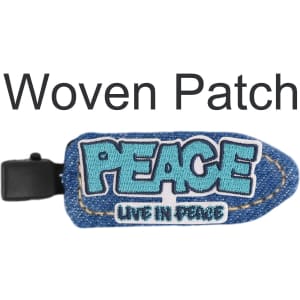 A denim duck bill hair clip in blue with a woven patch displaying the word "PEACE". It features a logo on the clip.